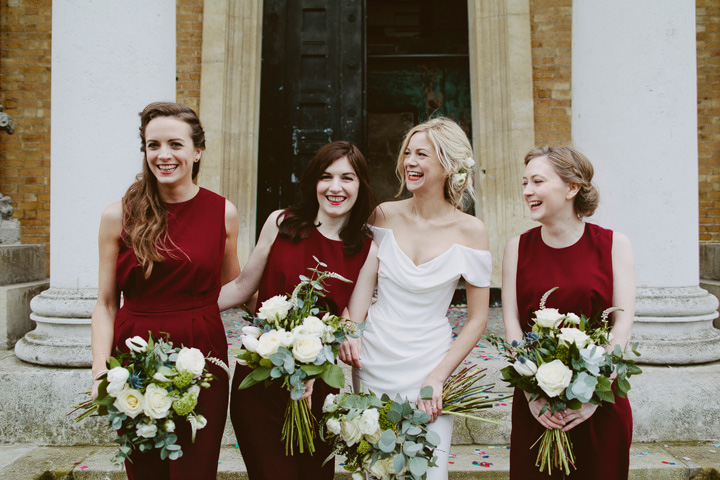 Bridesmaids in burgundy jumpsuits in front of the Asylum chapel