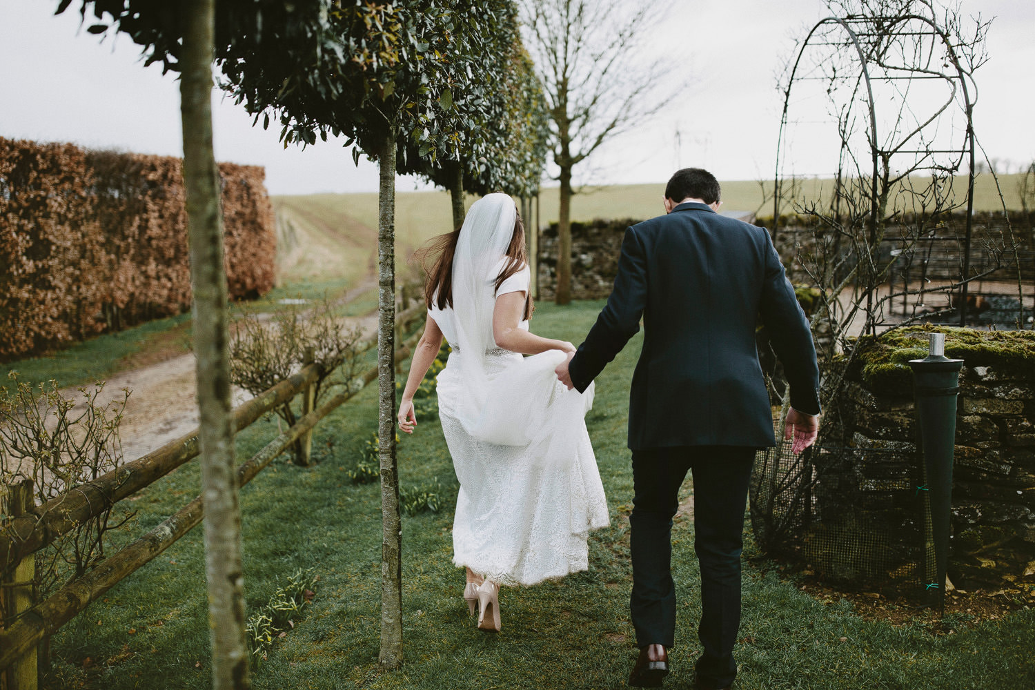 Bride and groom walk in the grounds of Cripps barn