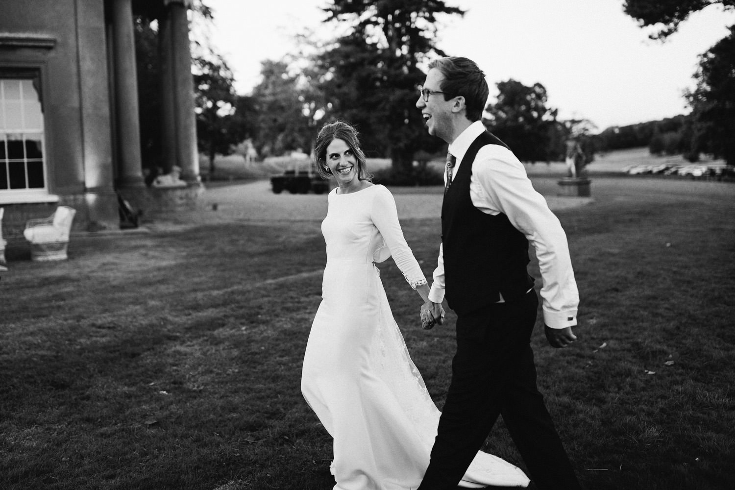 Bride wearing Rime Arodaky walks with groom in the evening light smiling