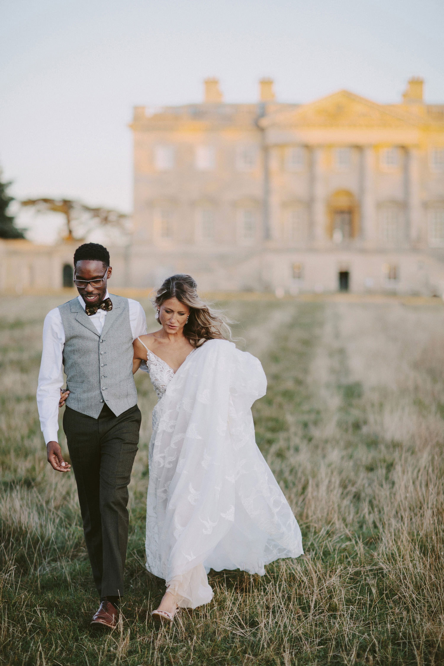 bride and groom walking in front of Kirtlington park in the sunset