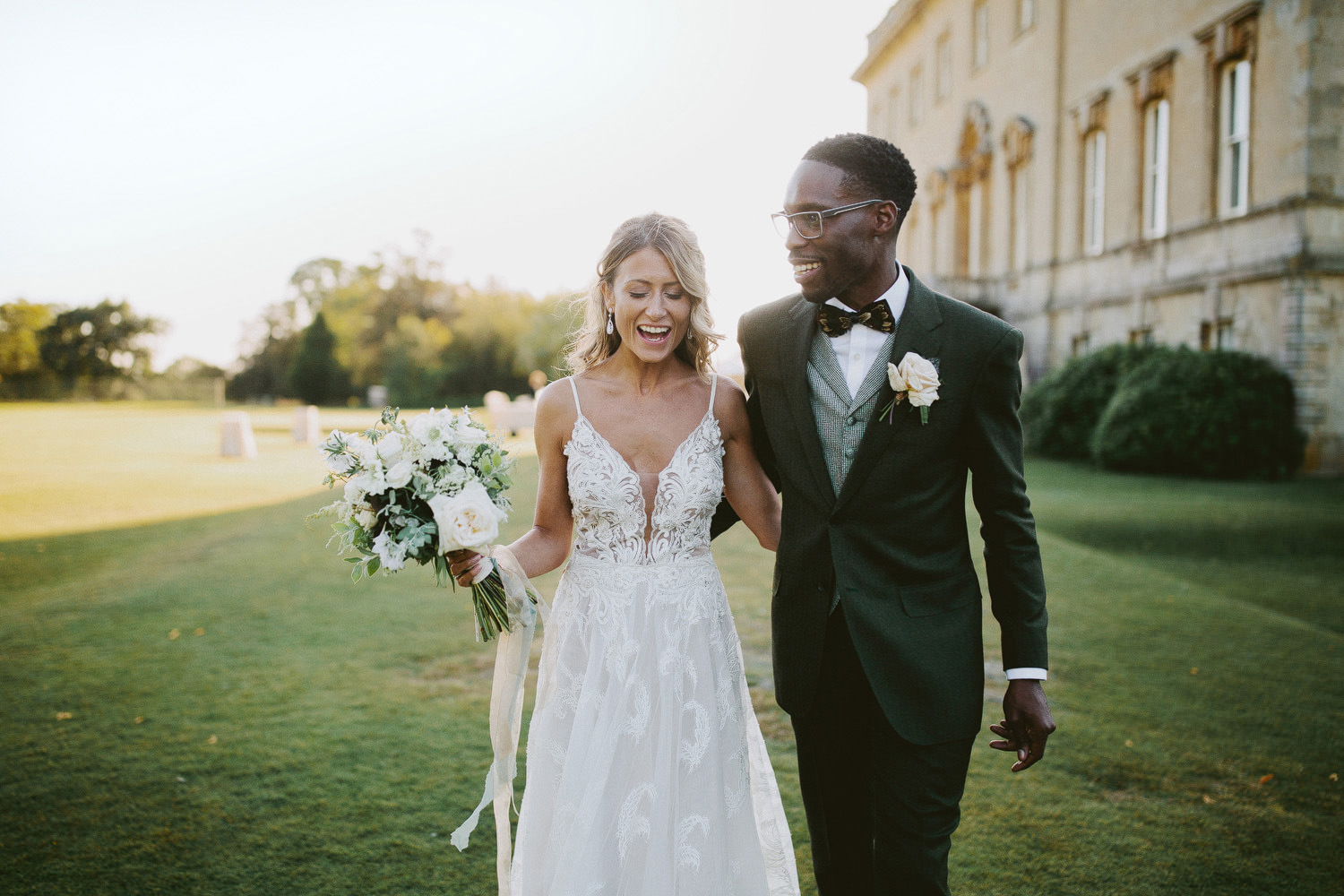 bride and groom laughing in sunset in the ground of a manor house