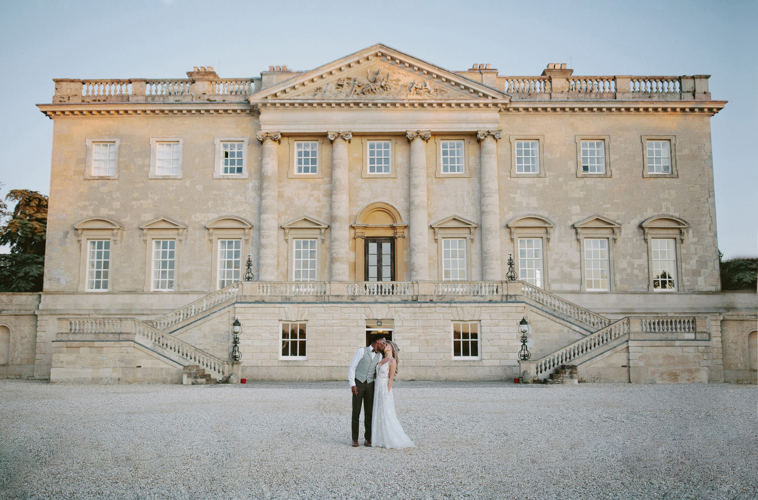 bride and groom kiss in front of Kirtlington park in Oxfordshire