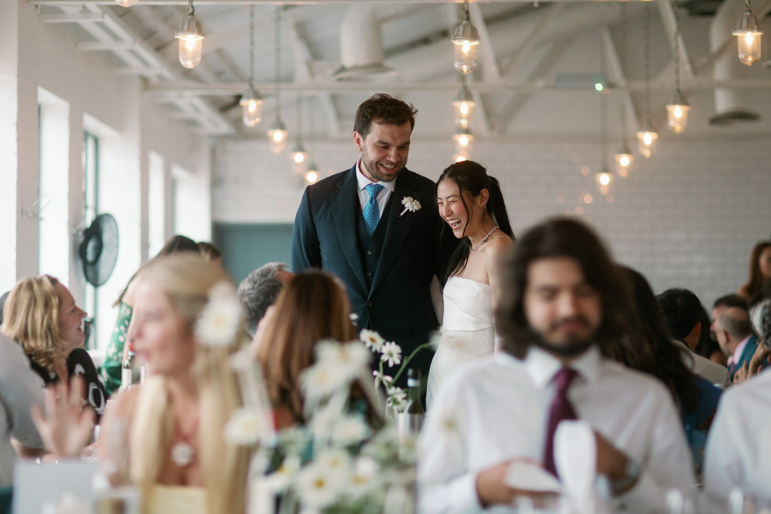 bride and groom laughing with friends in restaurant 
